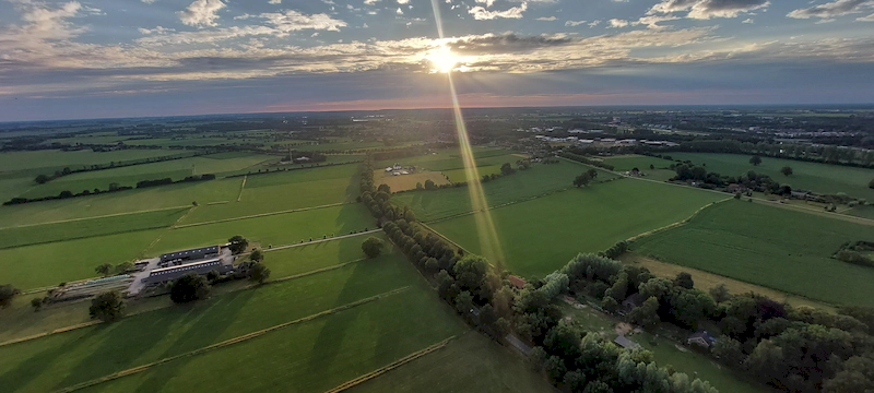 Ballonvaart boven de Achterhoek met uitzicht over velden en dorpen bij zonlicht